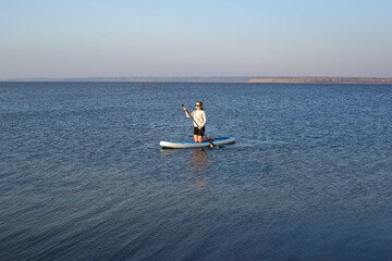 Young woman on stand up paddle board. Stand up paddle boarding on a quiet lake
