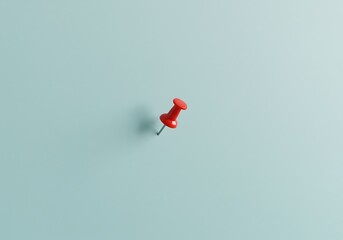 Minimalist close-up of a single red pushpin stuck into a light blue wall, casting a soft shadow—symbolizing focus, reminder, or planning.