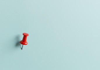 Minimalist close-up of a single red pushpin stuck into a light blue wall, casting a soft shadow—symbolizing focus, reminder, or planning.