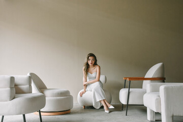 Young Asian woman sitting on a chair in a minimalist space.