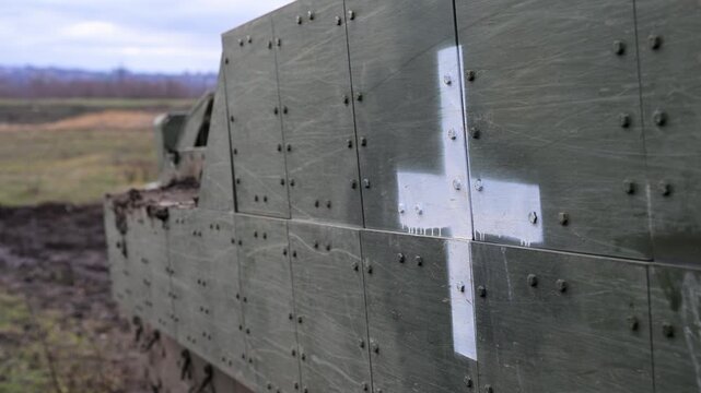A detailed shot of the bolted appliqu&eacute; armor on a US-made M2 Bradley in Ukraine. The stark white cross indicates its use as a frontline armored ambulance or MEDEVAC vehicle.