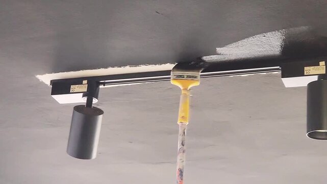 Touching up the ceiling edge cornices with black paint using a brush