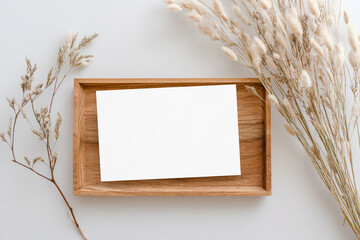 Blank card on wooden tray with dried flowers for mockup