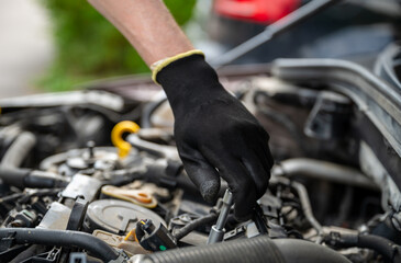 Mechanic hand in glove using socket wrench to repair car engine