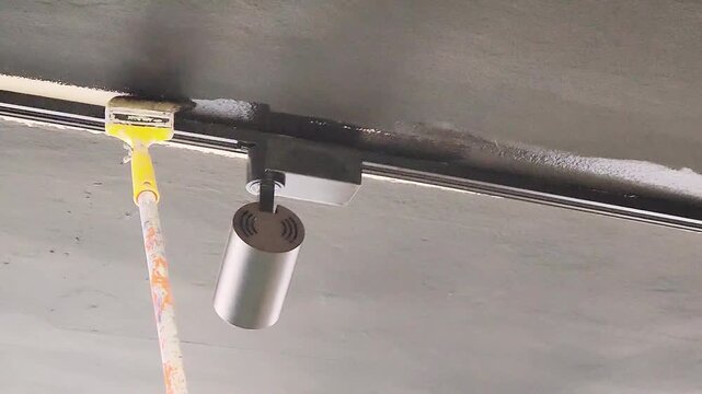 Touching up the ceiling edge cornices with black paint using a brush