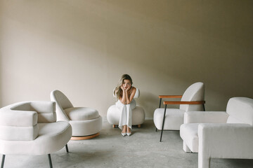 Young woman seated among modern minimalist chairs.