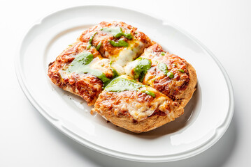 Rectangular pizza with melted cheese, tomato and pesto sauces on a white plate. Crispy crust, sliced into four pieces. Tasty homemade Italian meal.