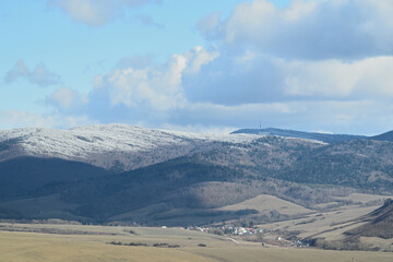 Blue sky with white clouds over mountain peaks at the end of winter