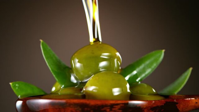 Super Slow Motion of Green Olives in Wooden Spoon with Pouring Oil . Filmed on High Speed Cinematic Camera at 1000 FPS