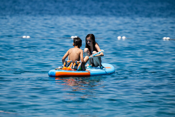 Children relaxing on inflatable sup board in the sea