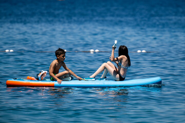 Children playing on paddle board in the sea