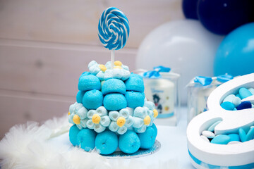 A delicious blue cake adorned with a colorful lollipop on top of it