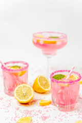 A cold pink refreshing drink with lemon and mint, chilled with ice cubes, decorated with a pink sugar rim. The best summer drink, rose lemonade on white background.