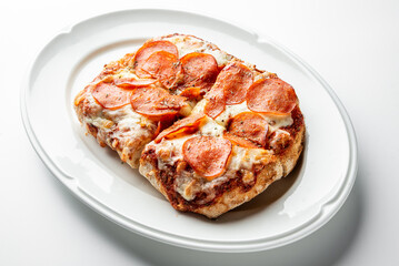 Freshly baked rectangular pepperoni pizza on a white plate, topped with melted cheese and crispy pepperoni slices, isolated on white background, perfect for food-themed content