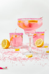 A cold pink refreshing drink with lemon and mint, chilled with ice cubes, decorated with a pink sugar rim. The best summer drink, rose lemonade on white background.