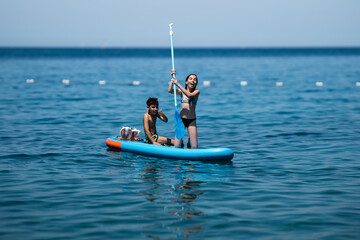 Happy children stand up paddling on turquoise sea during summer vacation