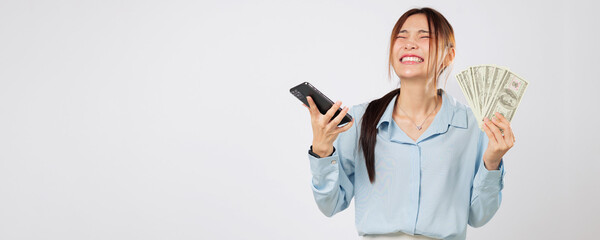 Happy Asian woman showing phone and holding money fan, online shopping winner excited about...