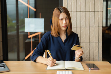 Asian woman stressed over credit card debt, holding bills in frustration. Financial anxiety and...