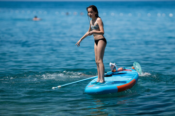 Girl balancing on paddle board in blue ocean water