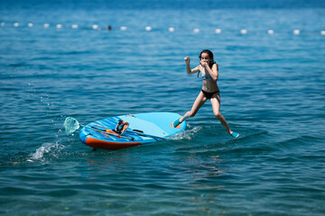 Girl jumping from paddleboard into clear blue water