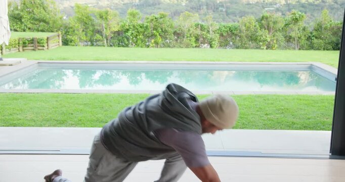 After unfolding yoga mat, Asian man performing hip flexor stretch on patio by pool seeking mobility