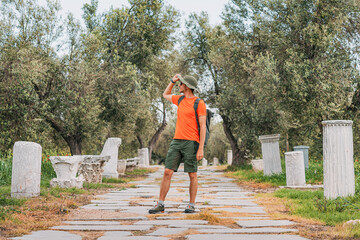 Tourist walking ancient Troy stone paved road between olive trees and ruins in Turkey, exploring...