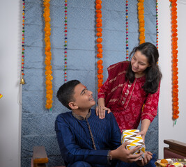 Girl with surprise gift for her brother on the occasion of traditional Indian festival like...
