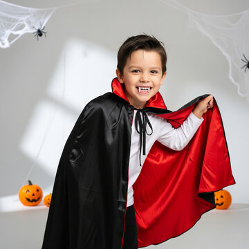 A little boy in a fun Halloween vampire costume &mdash; black cape with red lining, white shirt, and plastic fangs