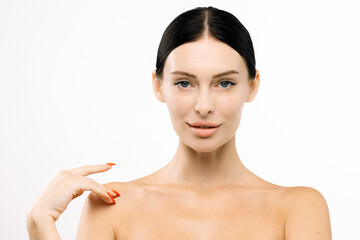 Beautiful woman with clear skin and dark hair, gently touching her shoulder, showcasing a natural...