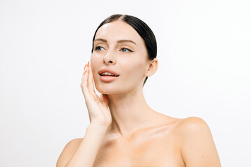 Caucasian woman with clear skin gently touching her face, showcasing a natural beauty routine...