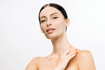 Beautiful woman with clear skin and sleek black hair poses gracefully against a white background,...