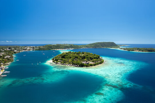 Drone photo of Iririki Island resort in Port Vila Harbour, Vanuatu. Idyllic holiday destination with clear water, boats, and waterfront bungalows.