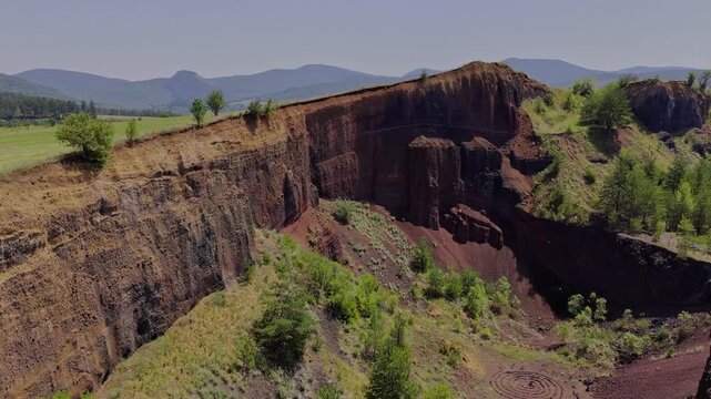 The extinct volcano from Racos, Romania. Aerial view of volcanic crater covered by green meadow and forest. View inside Volcano with lush vegetation in summer. Volcano ridge with vegetation. 