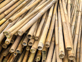 Close-up of horizontally stacked bamboo poles with earthy tones and visible grain. Natural sustainable material ideal for eco-construction, rustic backgrounds, and organic design themes.

