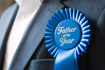 Close up of “Father of the Year” award ribbon pinned to man’s suit chest. Celebration of fatherhood and recognition