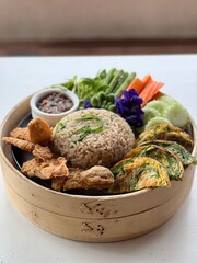 Table top view shrimp paste fried rice with vegetable and fried egg on the side, traditional Thai food.