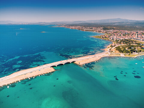 Scenic aerial view of the bridge connecting Cunda Island to mainland Ayvalik, Turkey, with boats and clear turquoise sea