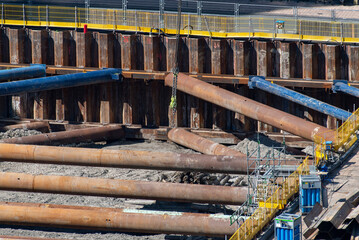 High angle view of excavation pit with sheet pile wall and large steel pipes for excavation pit shoring or supporting the sides of a construction site