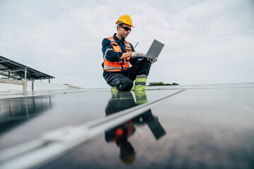 Solar energy technician monitors equipment on rooftop installation in bright afternoon light