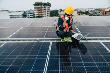 Worker inspects solar panels on a rooftop while using a laptop in an urban environment during the day