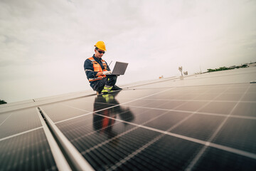 Technician works on solar panels while using a laptop on a rooftop in a modern solar energy installation