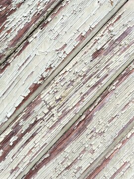 Closeup of diagonal wooden boards with peeling white paint abstract background texture