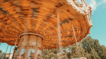 Swinging carousel ride in motion with blurred background and blue sky