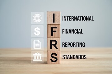 Wooden blocks spelling out ifrs international financial reporting standards with financial icons on a light background symbolizing global accounting practices