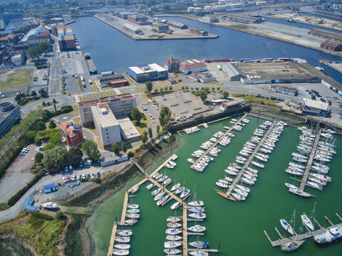 Aerial view of the shimmering marina embracing countless yachts contrasting with the industrial port, Dunkirk, France.