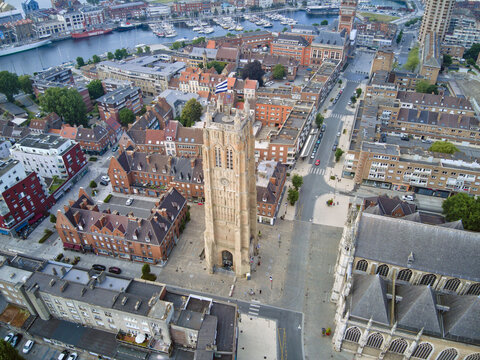 Aerial view of the striking belfry tower piercing the skyline amidst the historical architecture of Dunkirk, blending old-world charm with modern urban life, Dunkirk, France.