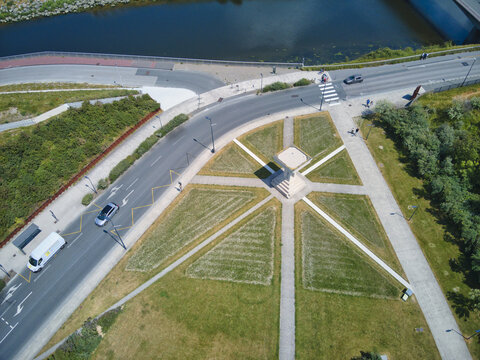 Aerial view of pathways forming a star shape on green grass near a bridge over a river, Dunkirk, France.