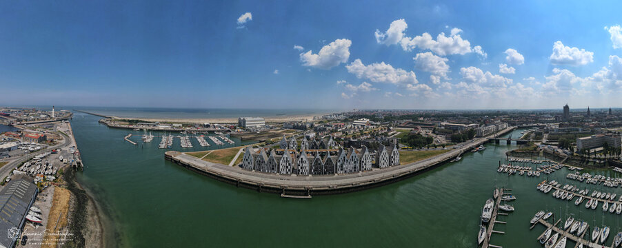 Aerial view of a picturesque harbor, where the sea meets the city, with boats nestled in the marina and modern buildings contrasting against the blue sky, Dunkirk, France.