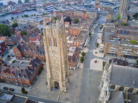 Aerial view of the towering Saint-Eloi's Church, its intricate stonework contrasting with the red-tiled roofs and the distant harbor, Dunkirk, France.