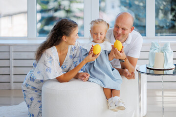 Family enjoying a cheerful moment indoors with fruits in a bright, modern living space